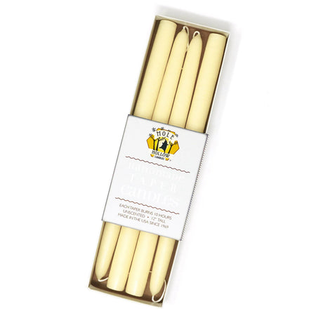 a box of four off-white taper candles in a rectangular box with a white label