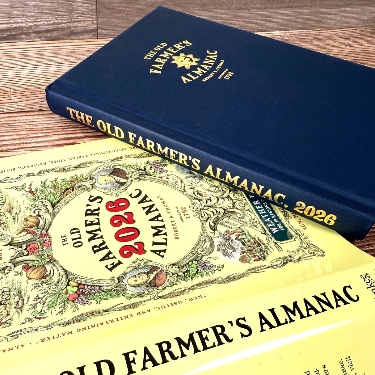 Two editions of The Old Farmer's Almanac on a wooden surface