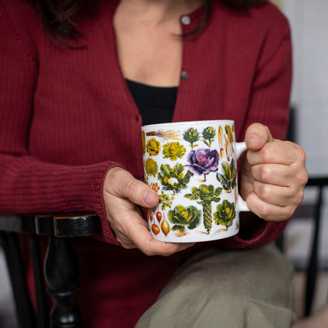 a seated model holds the vegetables mug with the handle in her left hand