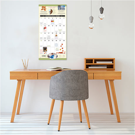 Wooden desk with gray chair and calendar on wall in room