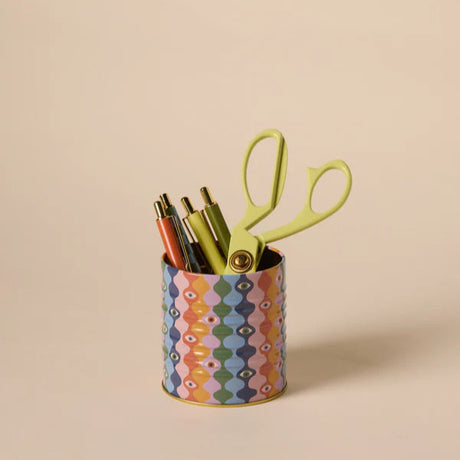 Colorful geometric-patterned canister with pens and scissors on a beige background