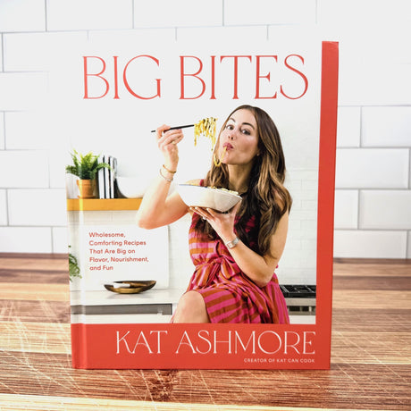 Book cover of 'Big Bites' by Kat Ashmore with a woman eating noodles.