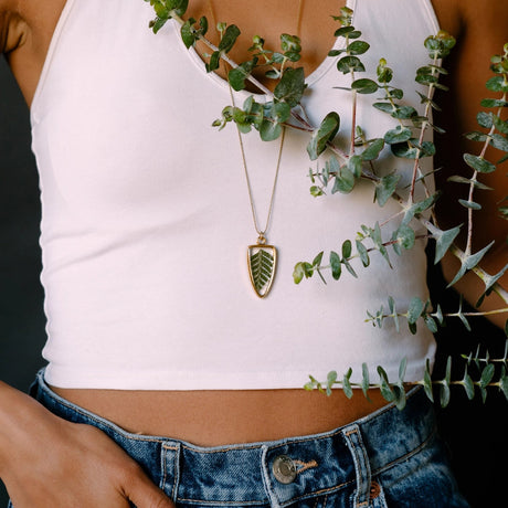 a model wearing the Pressed Fern Arrow Necklace seen from neck to torso showing that the 30" chain lands about mid-torso on the model