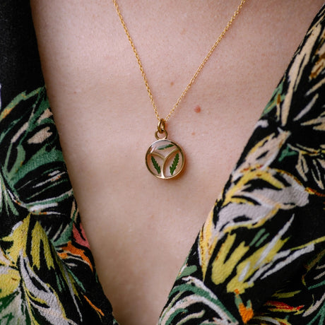 a close up of a model wearing the Pressed Fern Arrow Necklace showing the pendant resting against her chest a few inches below her collarbone