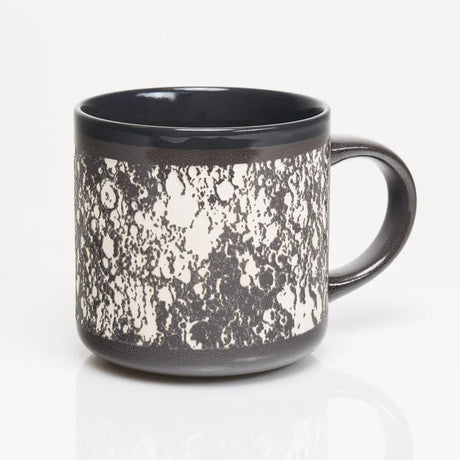 the other side of the gray ceramic mug with wrap around carved details of the surface of the moon in white