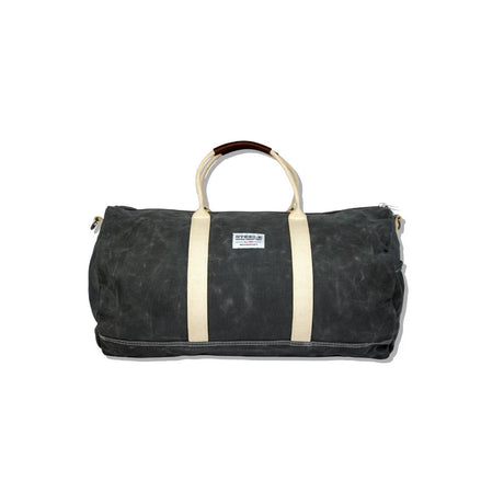 a gray waxed canvas duffle bag with white straps and leather handles