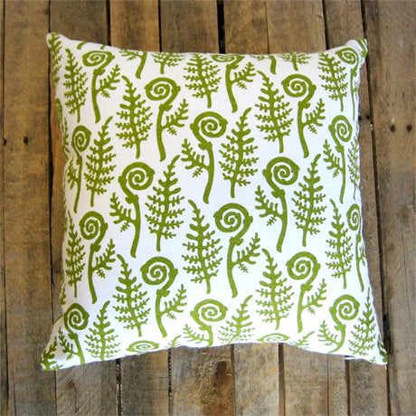 Decorative pillow with green fern pattern on a wooden background