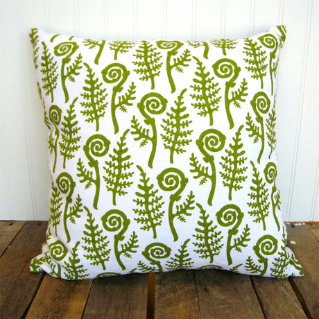 Decorative pillow with green fern pattern on a wooden surface