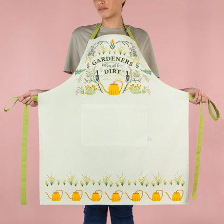 Person wearing a white apron with gardening-themed design on a pink background
