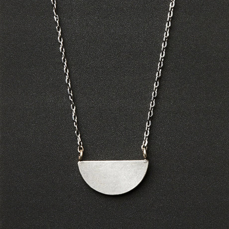 A silver necklace with a half moon pendant