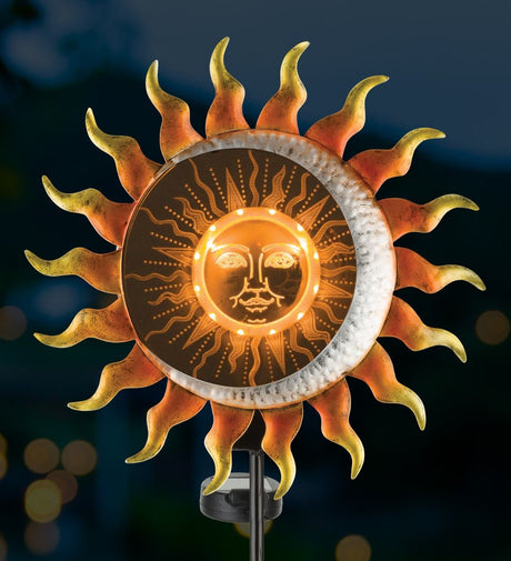 Illusion solar stake glowing at night, displaying the illuminated sun design with amber lights.