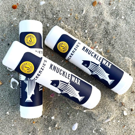 a trio of Knuckle Wax sticks on a sandy beach