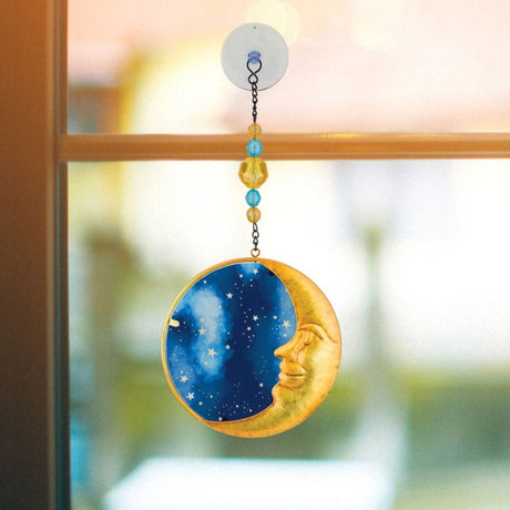the moon suncatcher hanging in a window
