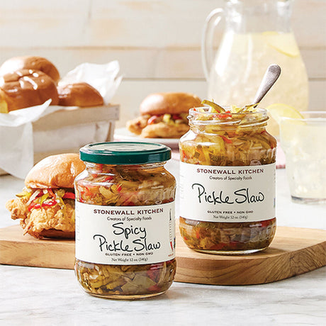 a tasty burger spread on a kitchen counter with two open jars of pickle slaw