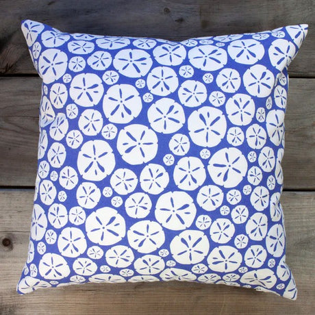 cornflower blue pillow with repeated sand dollar design on a wood surface