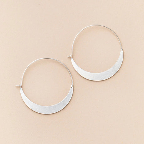 a pair of silver hoop earrings that take the shape of a crescent moon