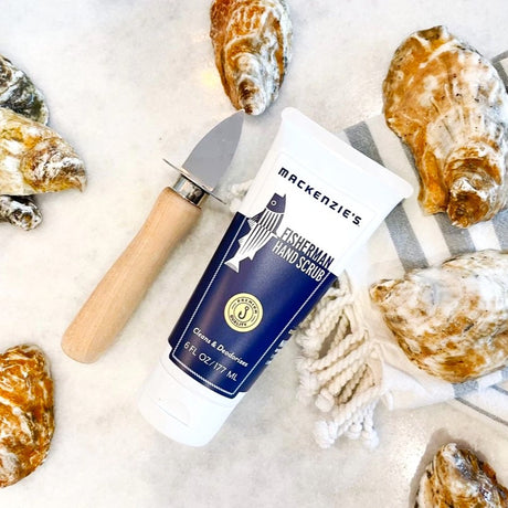 a bottle of the Fisherman Hand Scrub on a table next to an oyster shucker and oyster shells