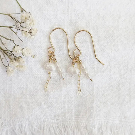 a pair of delicate gold earrings with tiny clusters of pearls dangling from a 14k gold chain