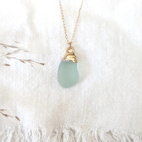 a delicate piece of aqua colored sea glass dipped in gold and suspended from a gold chain