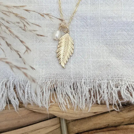 a charm necklace with a 14k gold fill leaf charm, and a lustrous freshwater pearl suspended on an 18" 14k gold fill chain