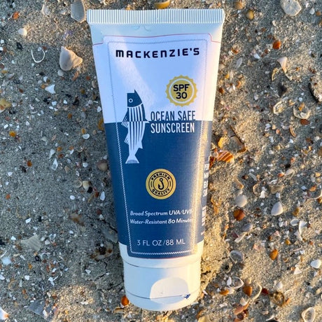 a blue and white sunscreen bottle on a sandy beach
