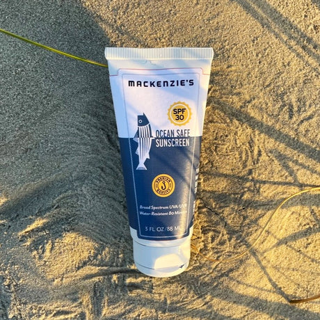 a blue and white sunscreen bottle on a sandy beach