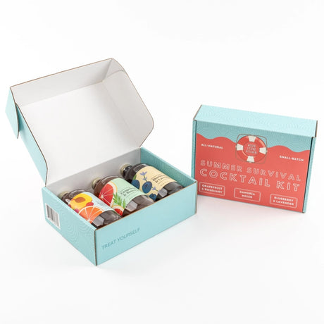 the open box of the summer survival kit showing all three bottles inside next to a closed box showing the full pale blue and coral graphics on the box