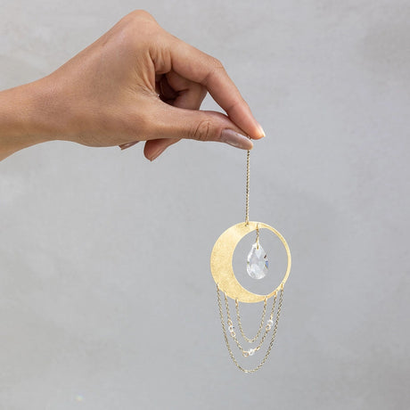 a hand dangling the mini crescent moon suncatcher to give an idea of scale