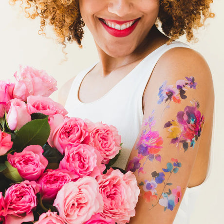 a model holding a bouquet of pink roses with the tattoos applied to her upper arm