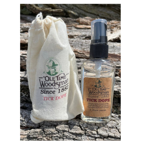 ole time woodsman Tick dope canvas pouch set next to the clear sprayer bottle on a natural tree bark background
