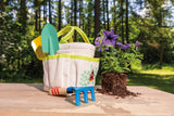 kids garden tote and tools on a table outdoors next to some flowers ready to be potted